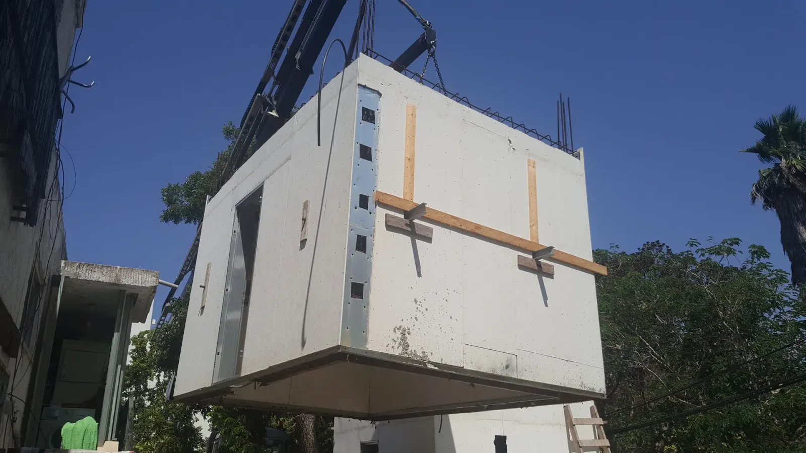 אלמנט מערכת iForm עם פתח דלת וזיון בולט, מונף במנוף לקראת הרכבה באתר, לפני יציקת הבטון