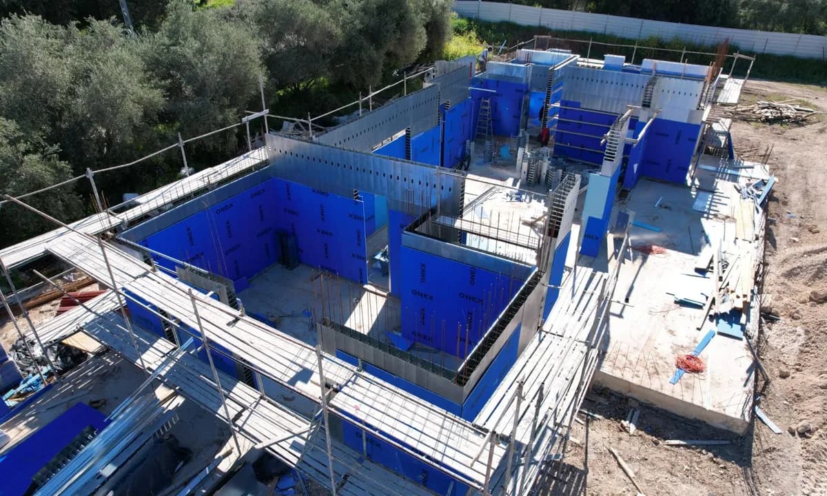 מבט אווירי על מבנה וילה בשלב הרכבת אלמנטי תבנית פלדה עם בידוד כחול מובנה, לפני יציקת הבטון, פרויקט שתי וילות בגבעת ישעיהו