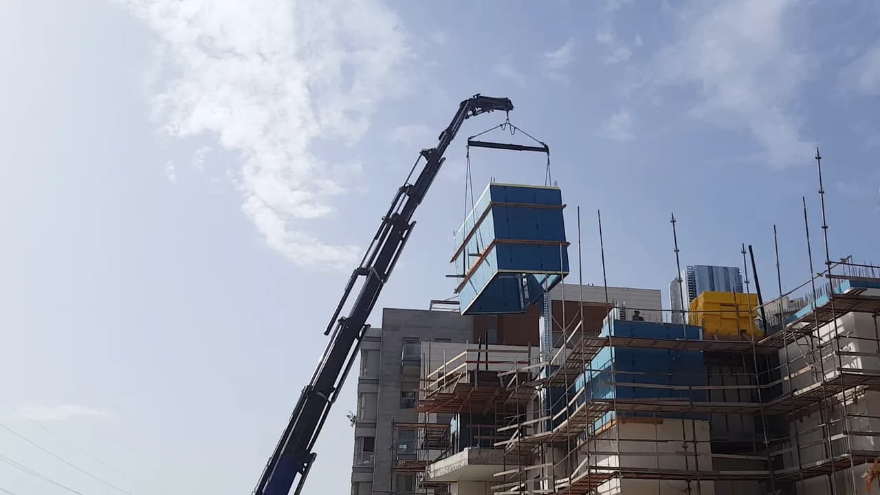 הנפת אלמנט מערכת iForm עם בידוד כחול במנוף מעל בניין מגורים בבנייה ברעננה